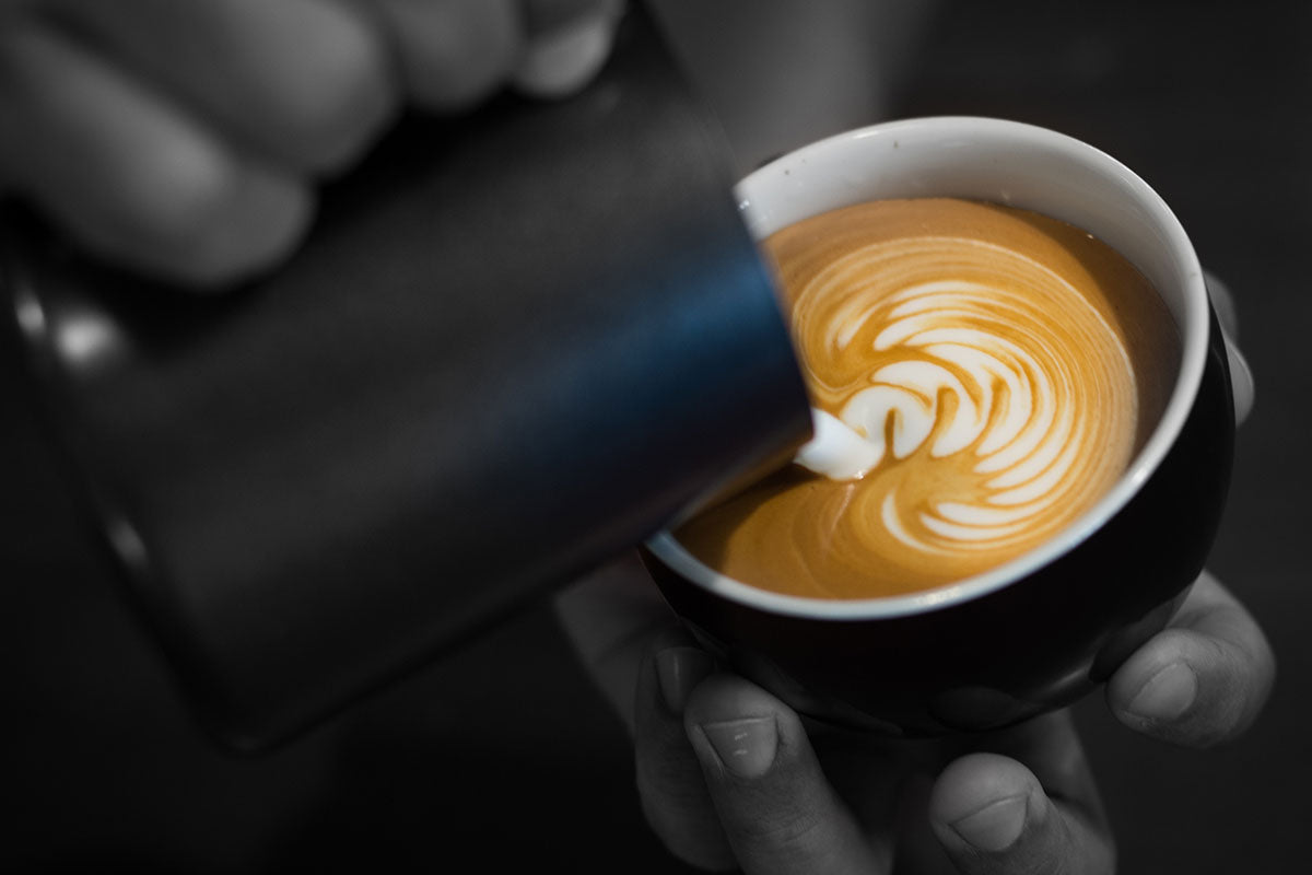 Image of milk being poured into coffee cup to create latte art